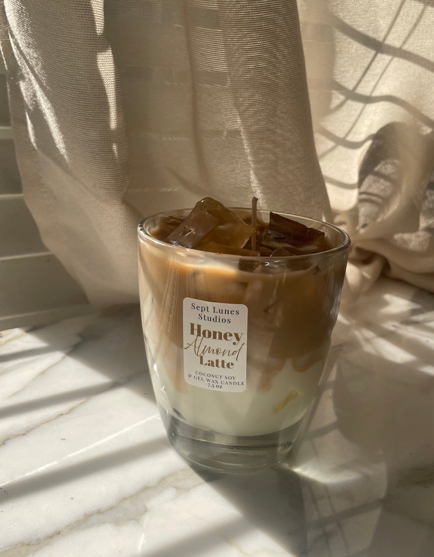 Glass of Honey Vanilla Latte with a label on a light surface with curtains in the background
