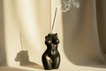 Black and gold decorative object resembling a female torso on a white background