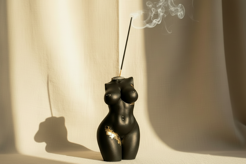 Black and gold decorative object resembling a female torso on a white background