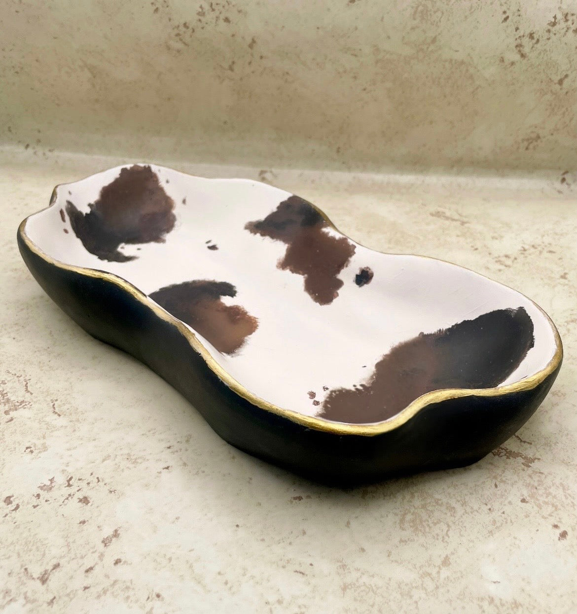 Ceramic dish with cow print design on a textured surface