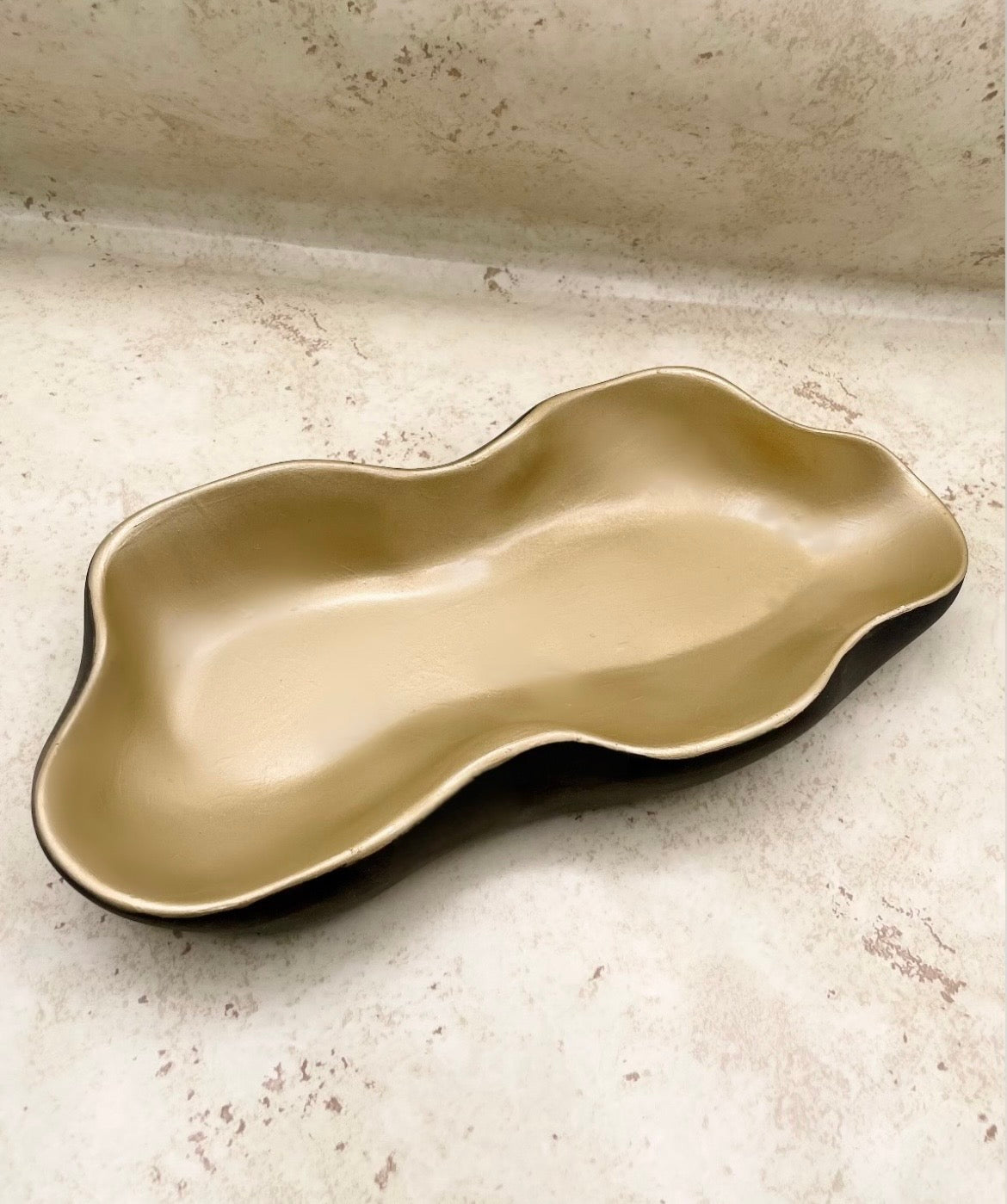 Wavy ceramic plate on a textured beige surface