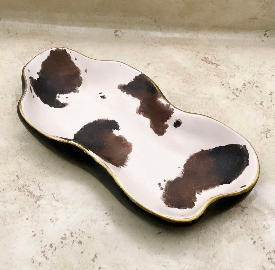 Ceramic dish with brown abstract patterns on a light gray surface