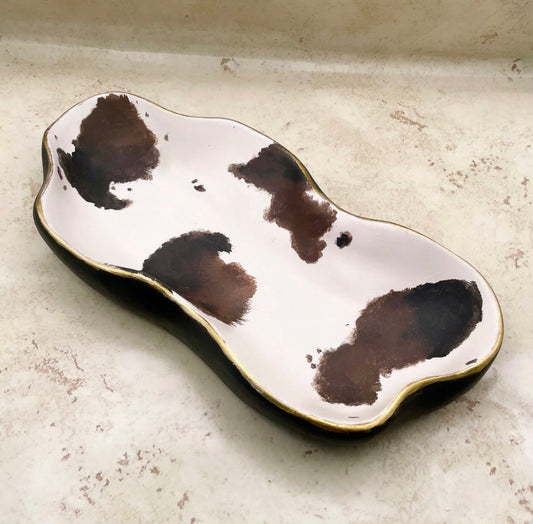 Ceramic dish with brown abstract patterns on a light gray surface